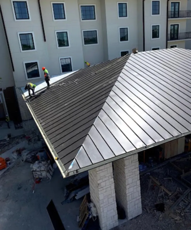 Crew installing standing seam metal roof panels on a commercial project in Hamburg